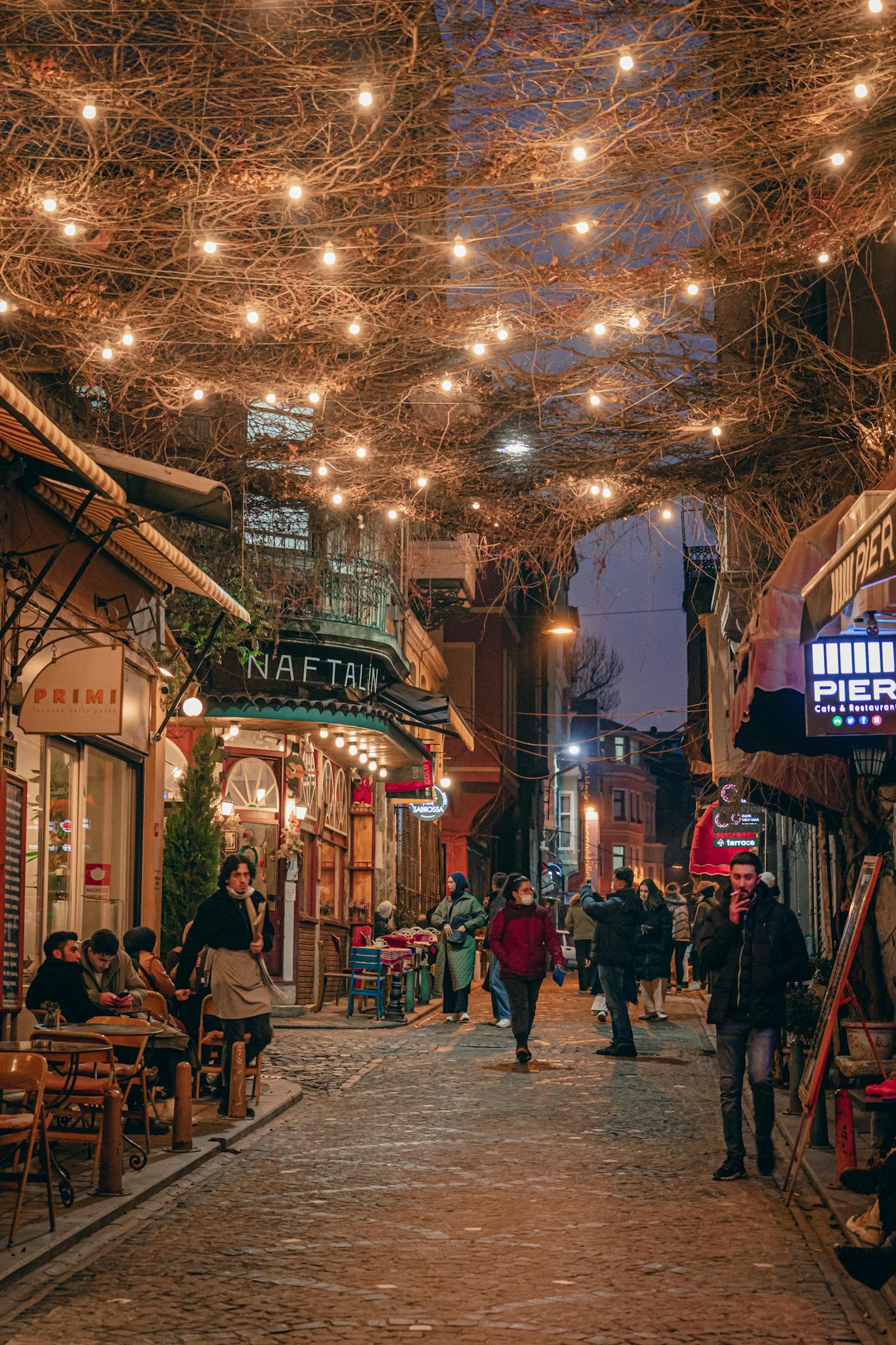 Cozy urban street in Istanbul with lights and people walking at night.