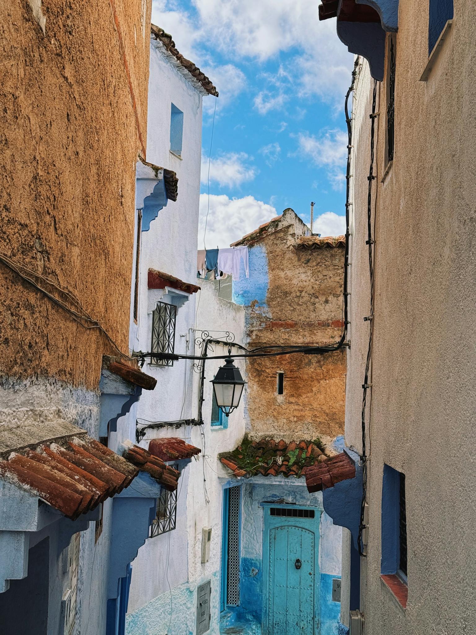 Picturesque alleyway with blue doors and walls in Chefchaouen, Morocco.