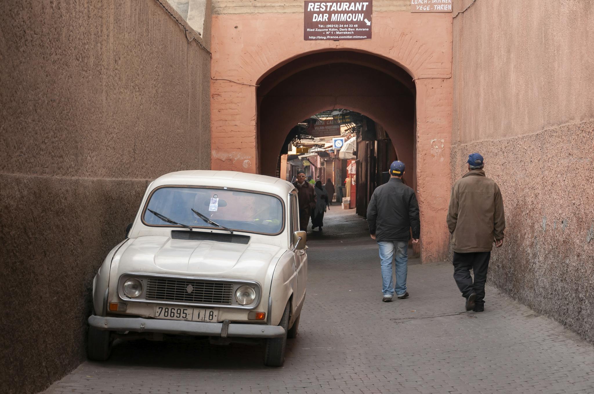 Street scene in Marrakesh with a vintage car and pedestrians. Captures local architecture and culture.
