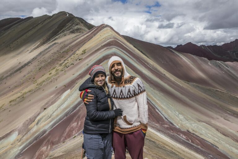 Couple posing at the vibrant Rainbow Mountain in Peru, showcasing adventure and travel spirit.
